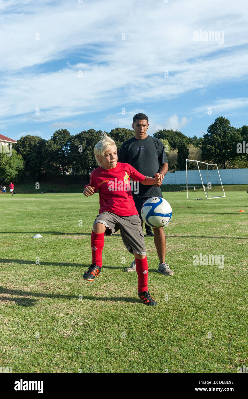 Junior giocatore di football la pratica di controllo di palla, pullman guardando, Cape Town, Sud Africa Foto Stock