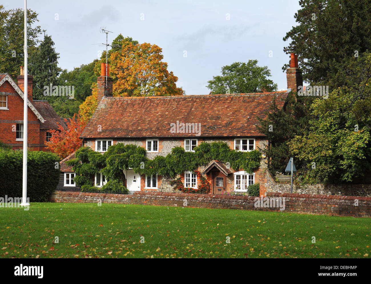Tradizionale English Village Cottages in inizio autunno con verde villaggio e pennone. Foto Stock
