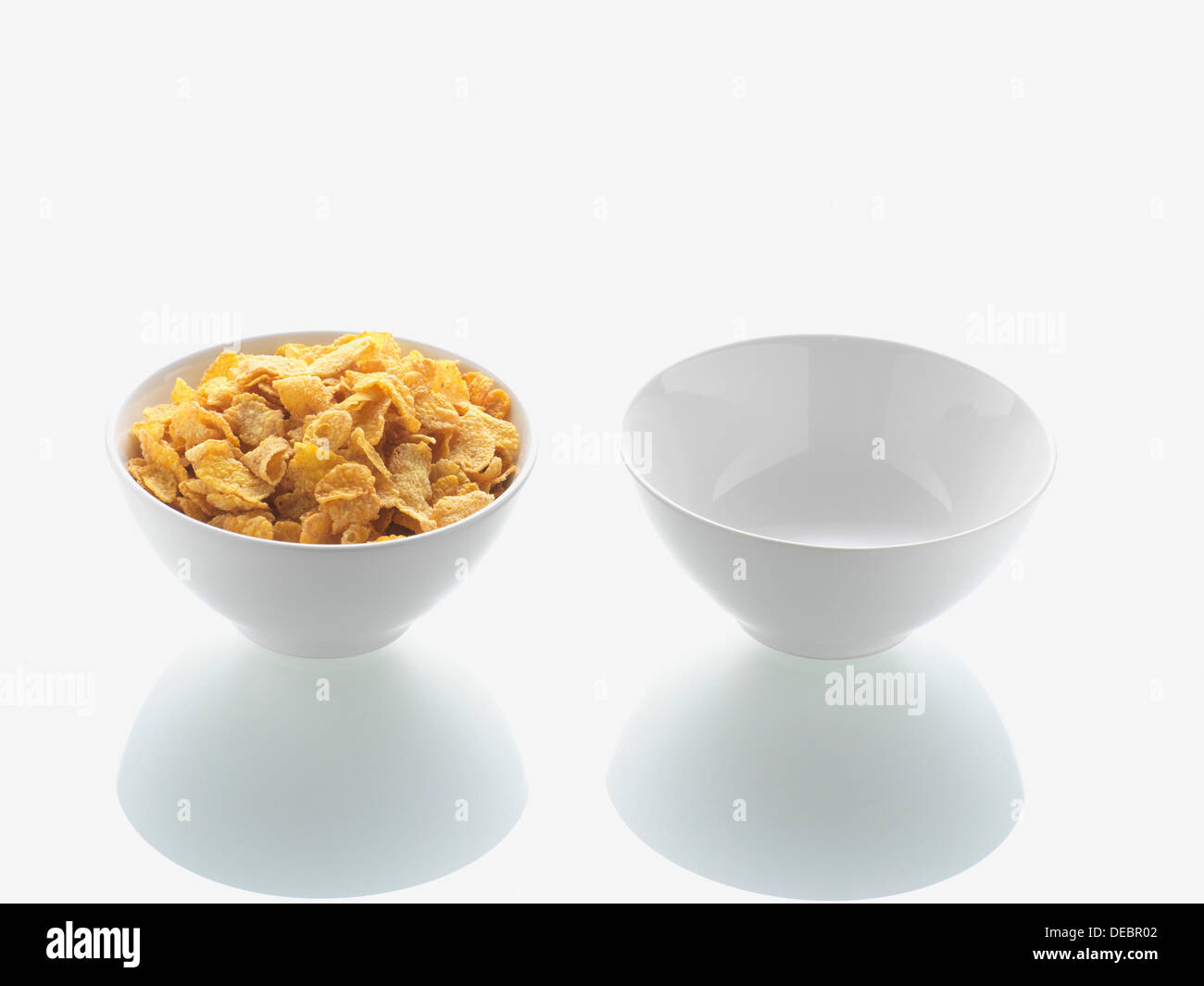 Piena ciotola di cornflake e recipiente vuoto Foto Stock