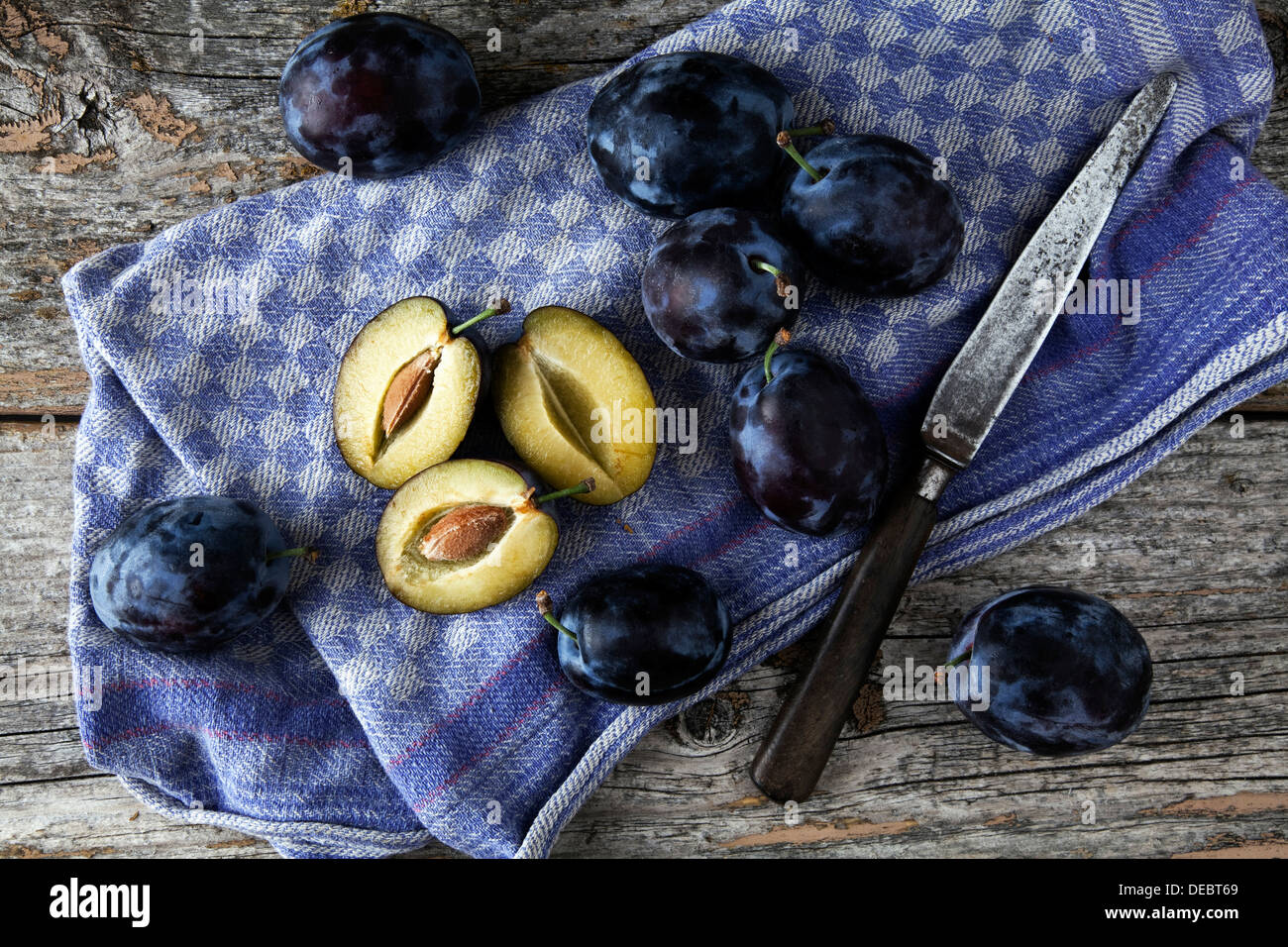 Prugne fresche (Prunus domestica) su un panno da cucina, con un coltello Foto Stock