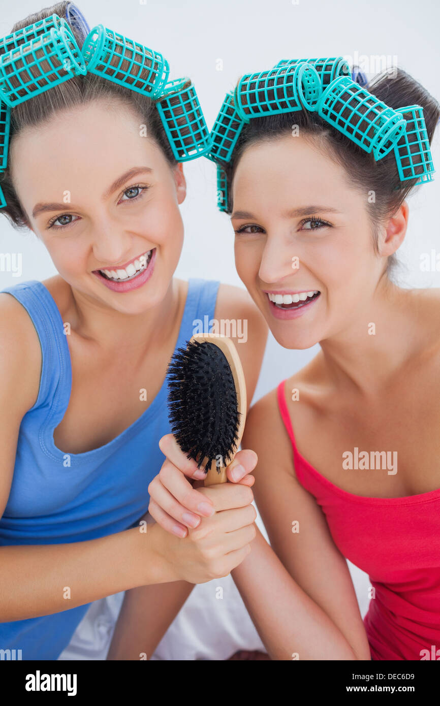 Felice ragazze in i capelli rulli holding spazzola per capelli Foto Stock