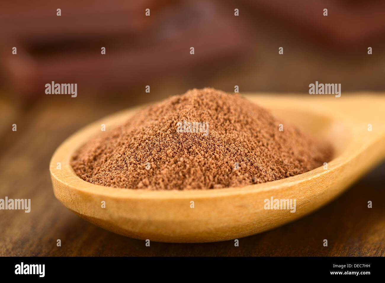 Cacao in polvere sul cucchiaio di legno con pezzetti di cioccolato in retro (molto leggera profondità di campo e la messa a fuoco di un terzo nel cacao) Foto Stock