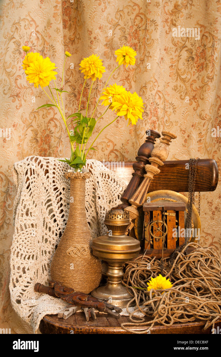 Ancora vita con antica orologeria, lampada a olio e fiori di colore giallo Foto Stock