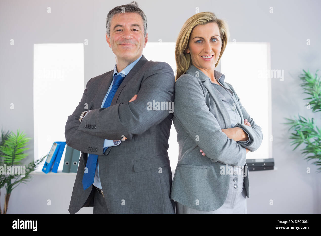 Due happy businessman guardando la fotocamera in piedi back-to-back Foto Stock