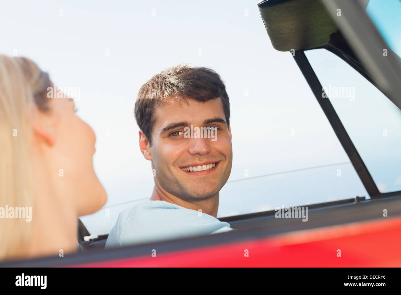 Uomo sorridente guardando la sua bella ragazza durante la guida Foto Stock