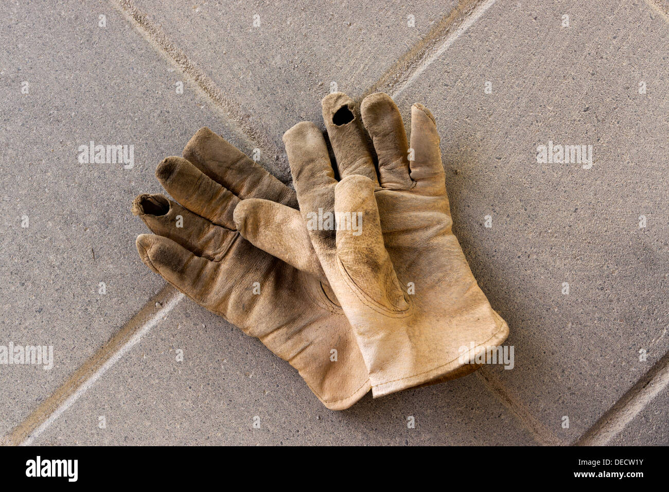 Usurati in pelle Guanti di lavoro giacente su un recentemente completato il patio in cemento. Foto Stock