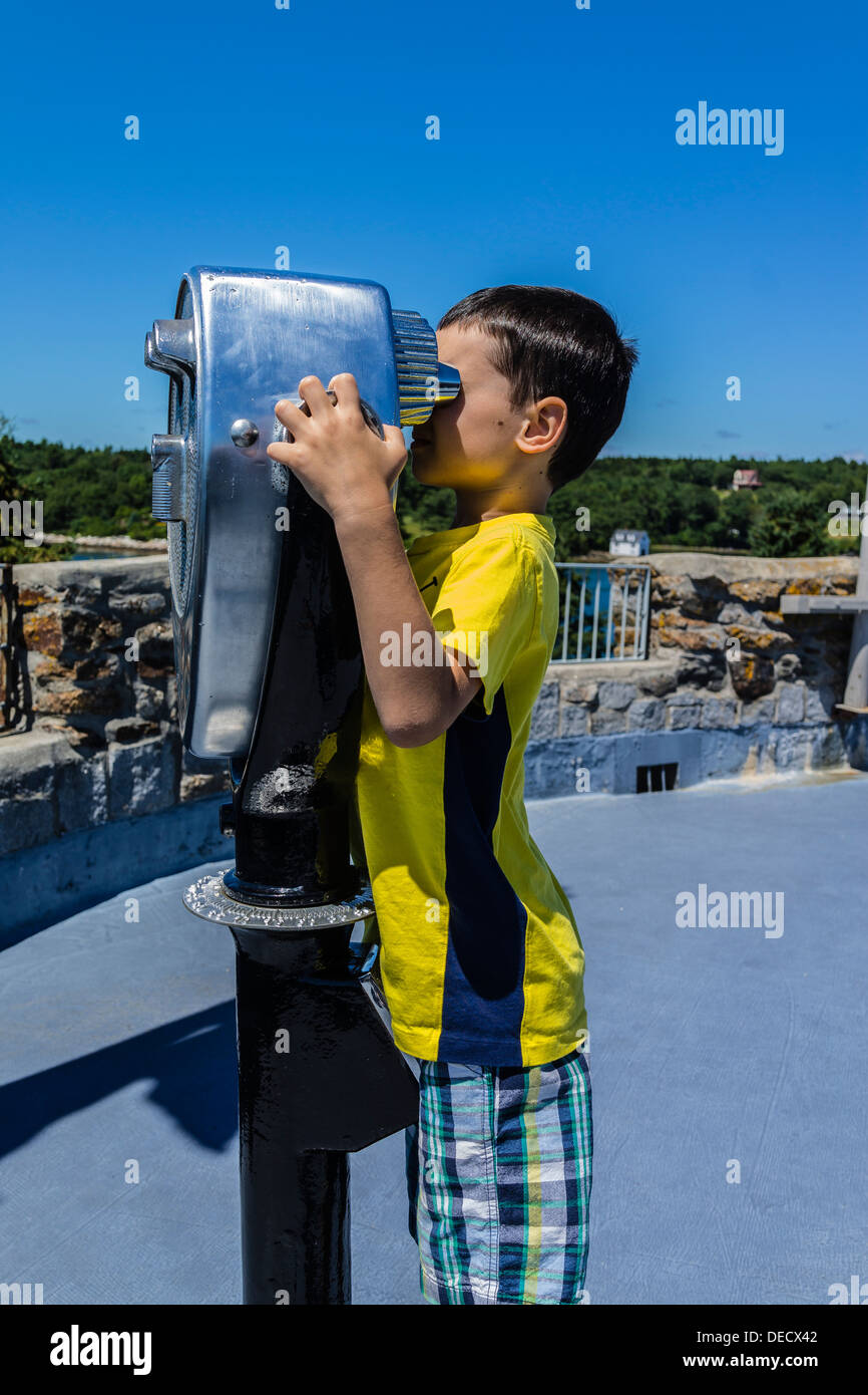 Un ragazzo cerca attraverso una gettoniera binoculare pubblica a Fort Frederick/Fort William Henry sito storico nel Maine. Foto Stock