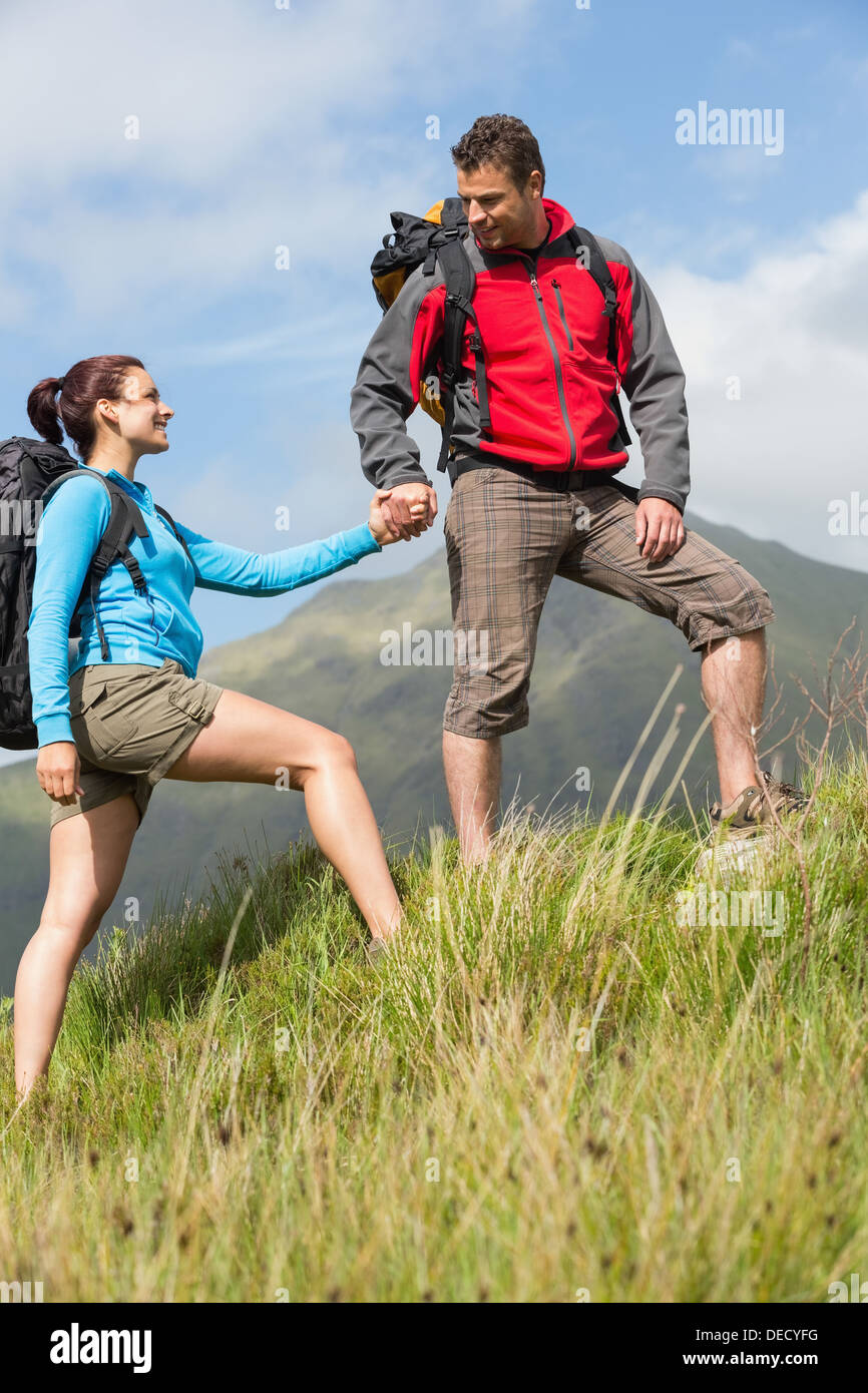 Bello escursionista aiutare la sua ragazza in salita Foto Stock
