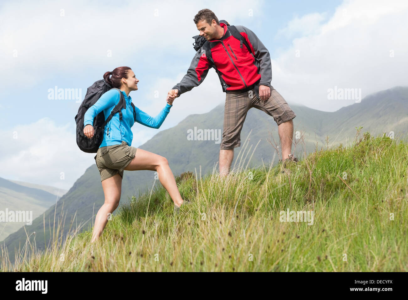 Attraente escursionista aiutare la sua ragazza in salita Foto Stock