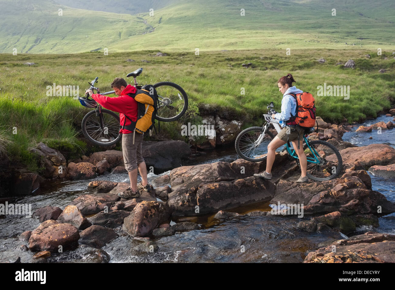 Paio di attraversare un fiume mantenendo le loro biciclette Foto Stock