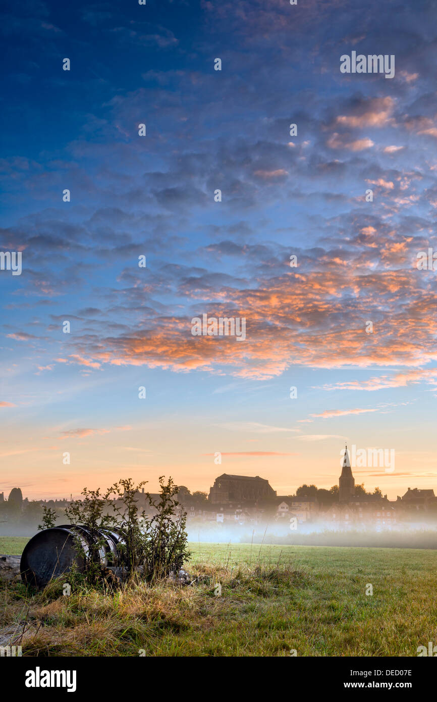 Malmesbury, Wiltshire. Le campane della chiesa anello lungo il prato in una nebbiosa settembre all'alba. Foto Stock