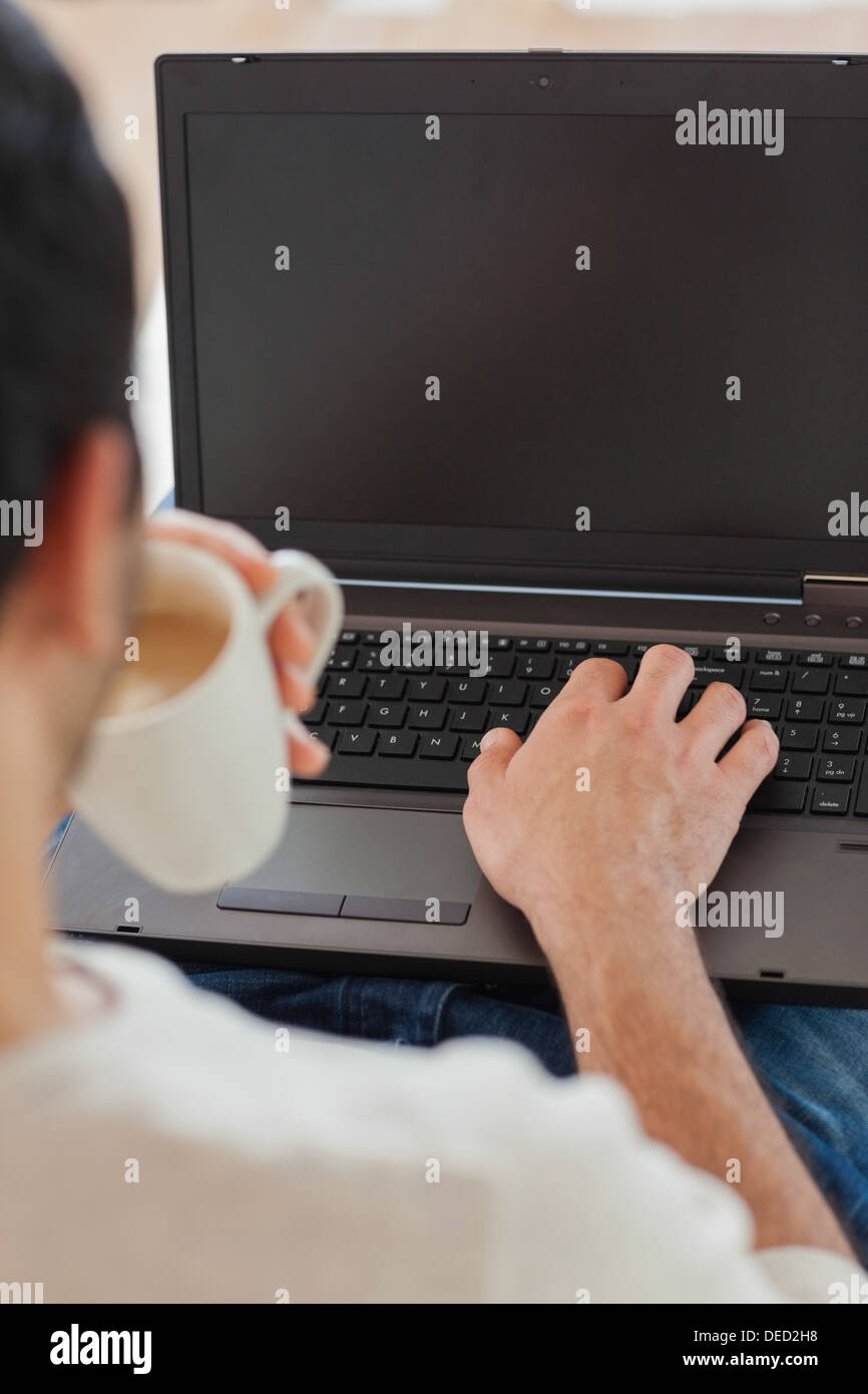 Sulla spalla vista del giovane uomo usando il suo computer portatile Foto Stock