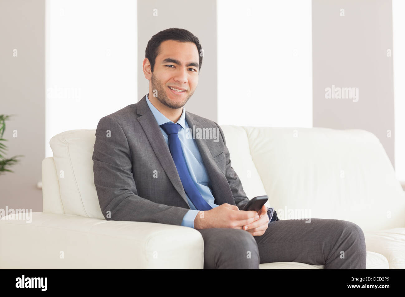Imprenditore sorridente seduto sul divano accogliente Foto Stock