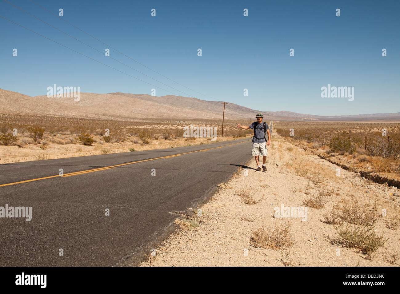 L'uomo autostop su un deserto rurale road - California USA Foto Stock