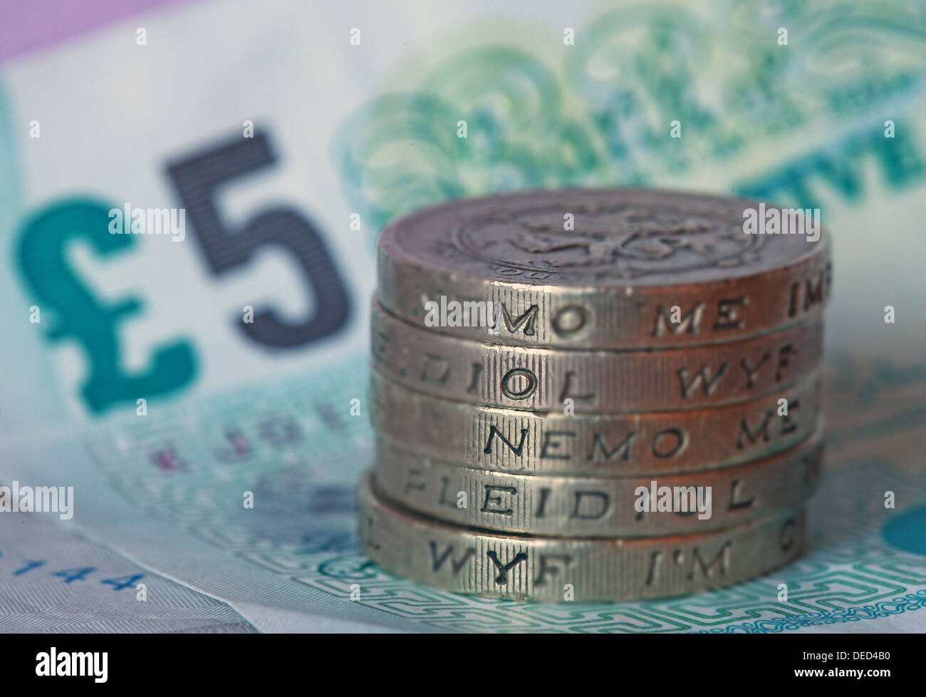 British Pound Sterling monete impilate scritto 'Strumenti', seduto su un REGNO UNITO Fiver Foto Stock