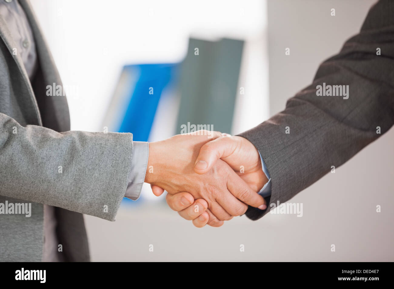 Due persone aventi una stretta di mano in un ufficio Foto Stock