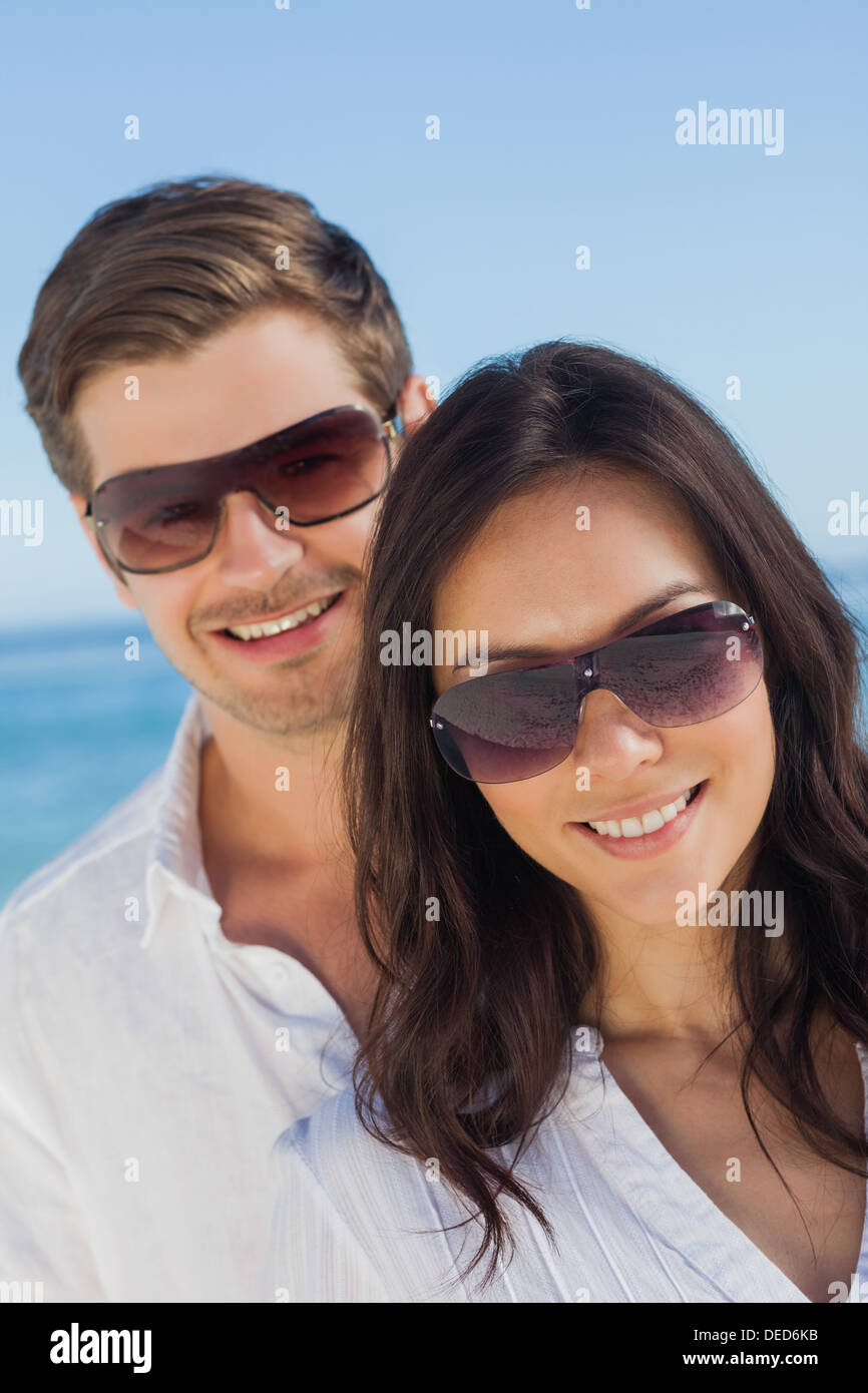 Coppia giovane indossando occhiali da sole e sorridente Foto Stock