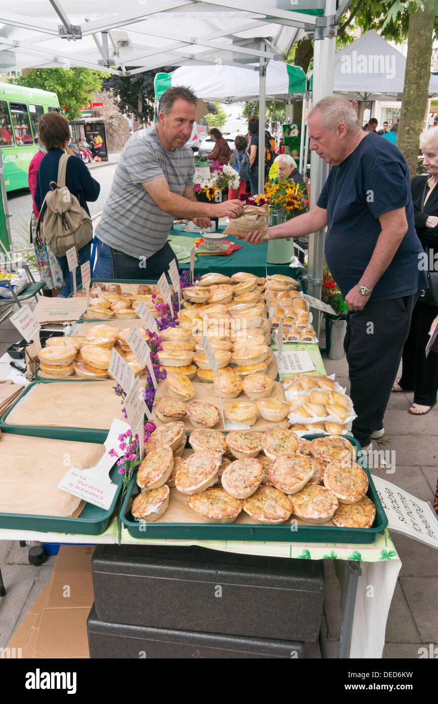 Uomo torta di acquisto da stallholder Exeter mercato agricolo, Devon, Inghilterra, Regno Unito Foto Stock