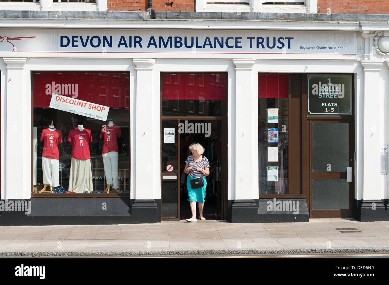 La donna lasciando la carità shop appartenenti a Devon Air Ambulance Trust, Exmouth Devon, Inghilterra, Regno Unito Foto Stock