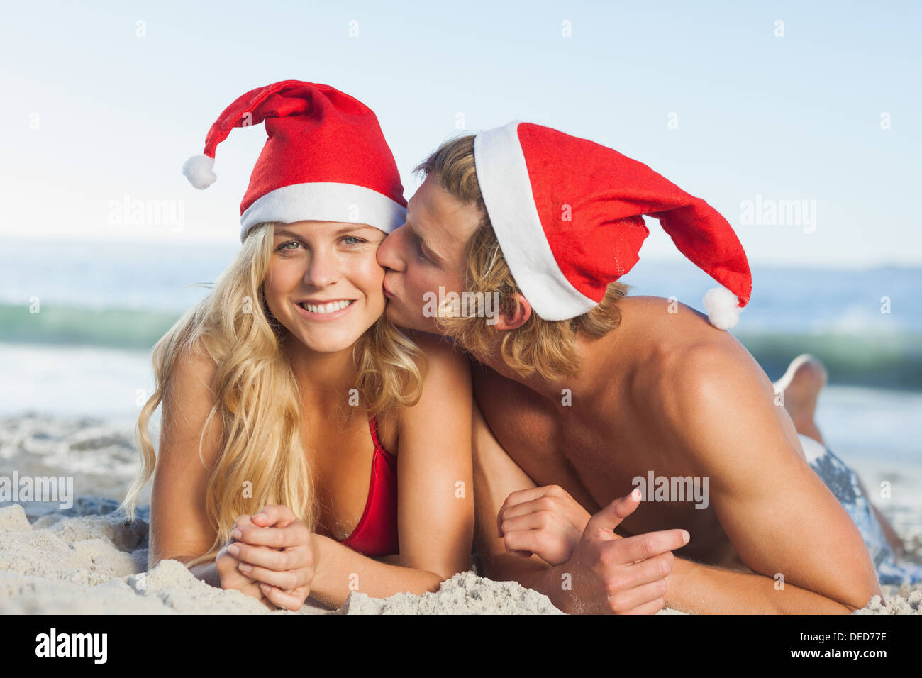 L uomo dando bacio al partner indossando cappelli di Natale Foto Stock