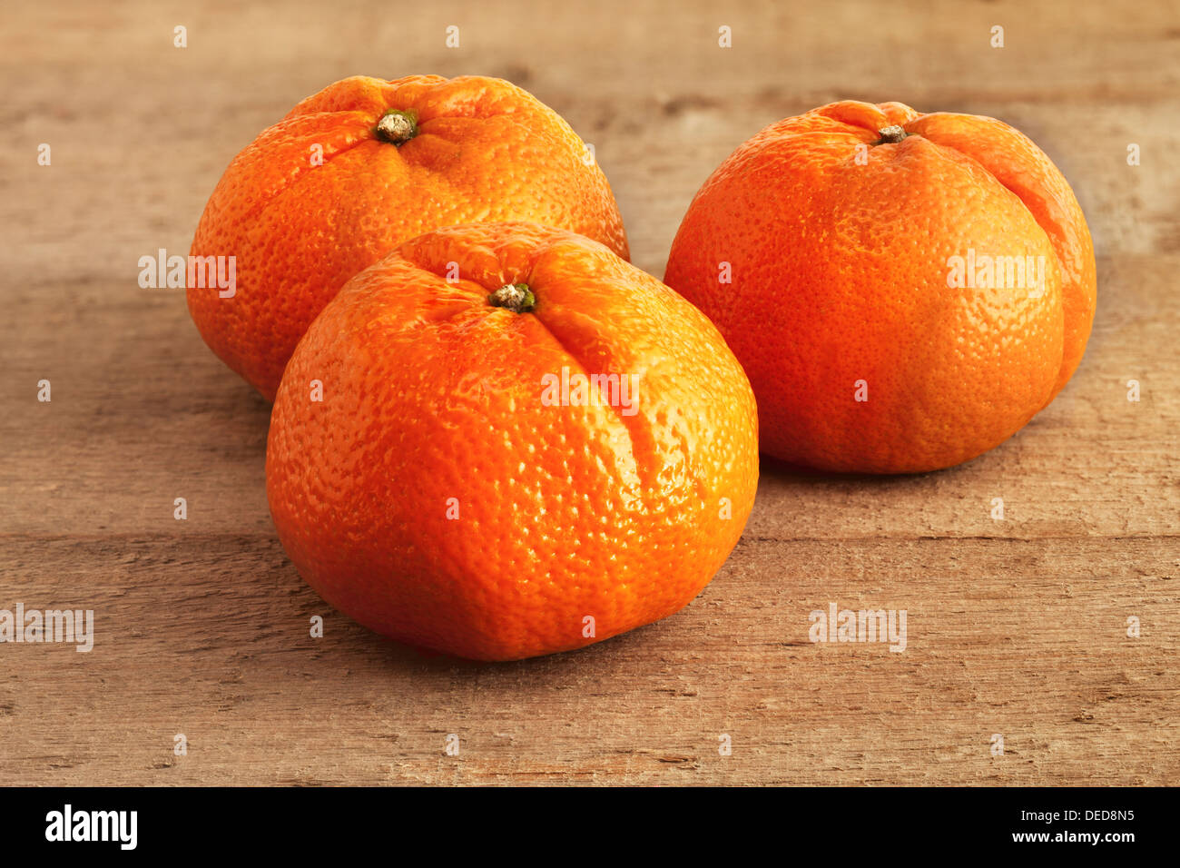 Mandarini arance - tre mandarini arance su un rustico di legno. Foto Stock