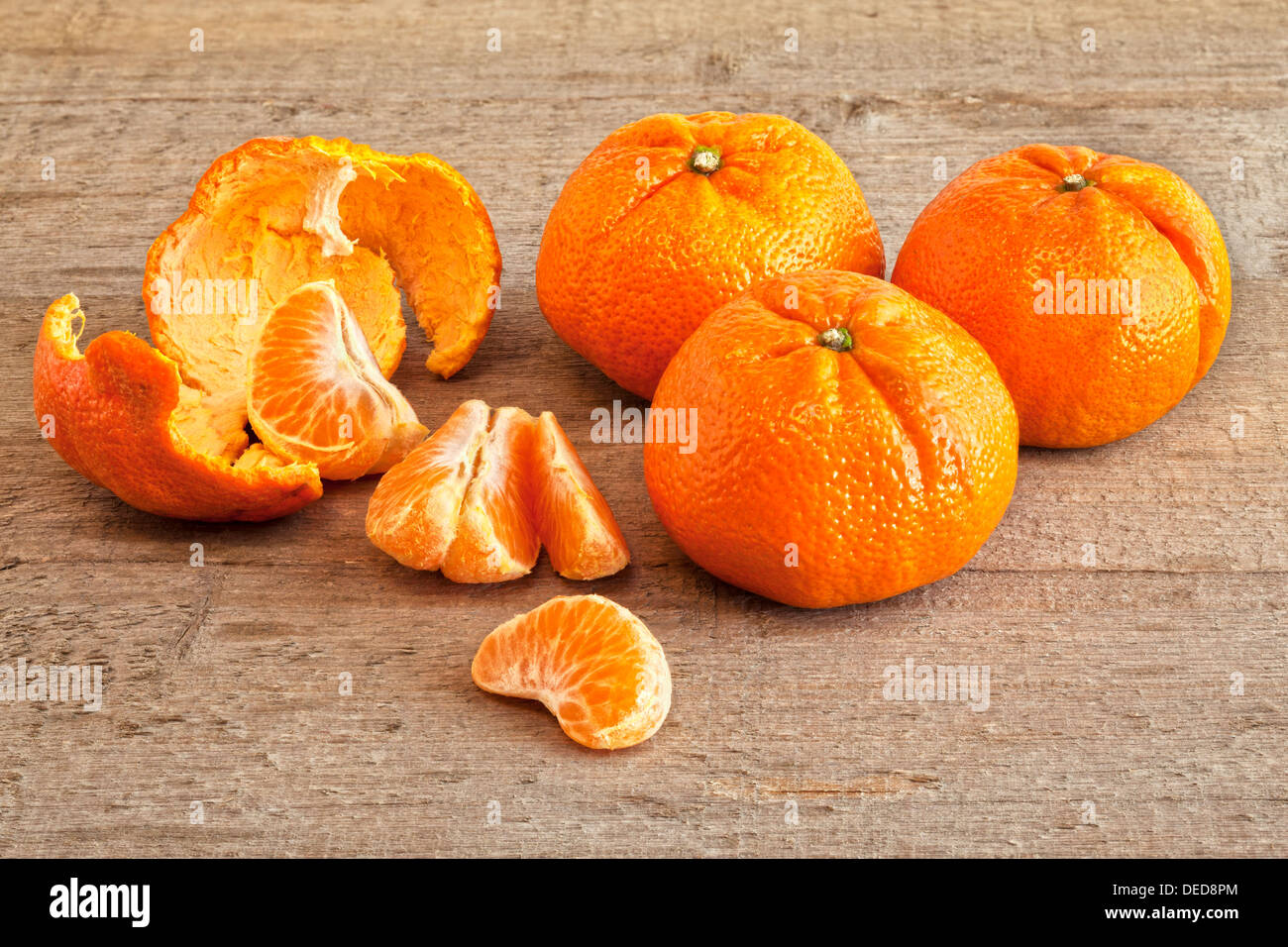 Mandarini Arance - Mandarini arance su un rustico di una superficie di legno, tre interi, uno pelato e segmentati. Foto Stock