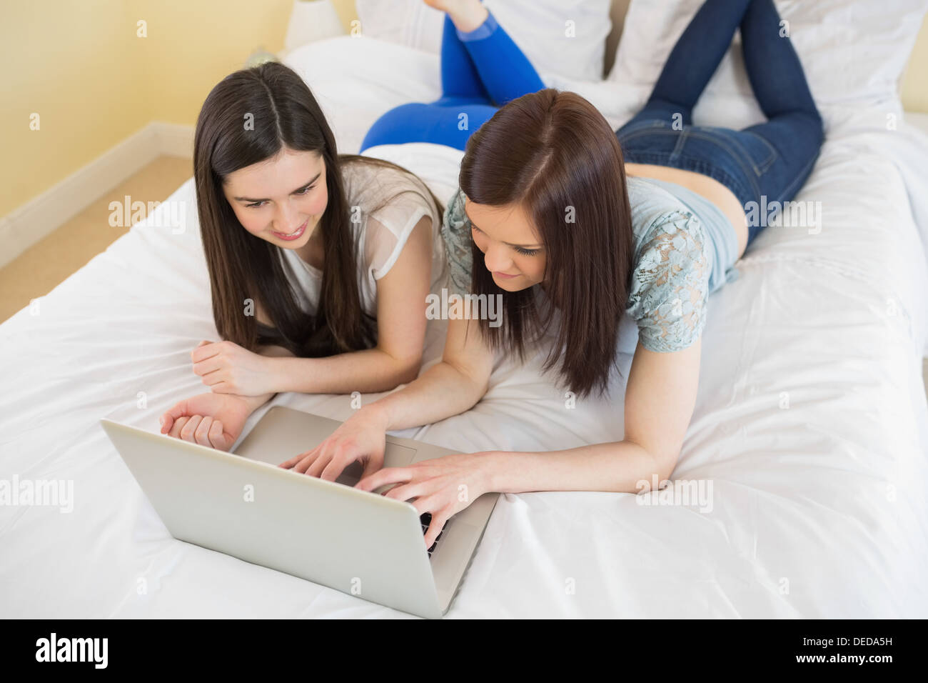 Happy amici usando un computer portatile giacente sul letto Foto Stock