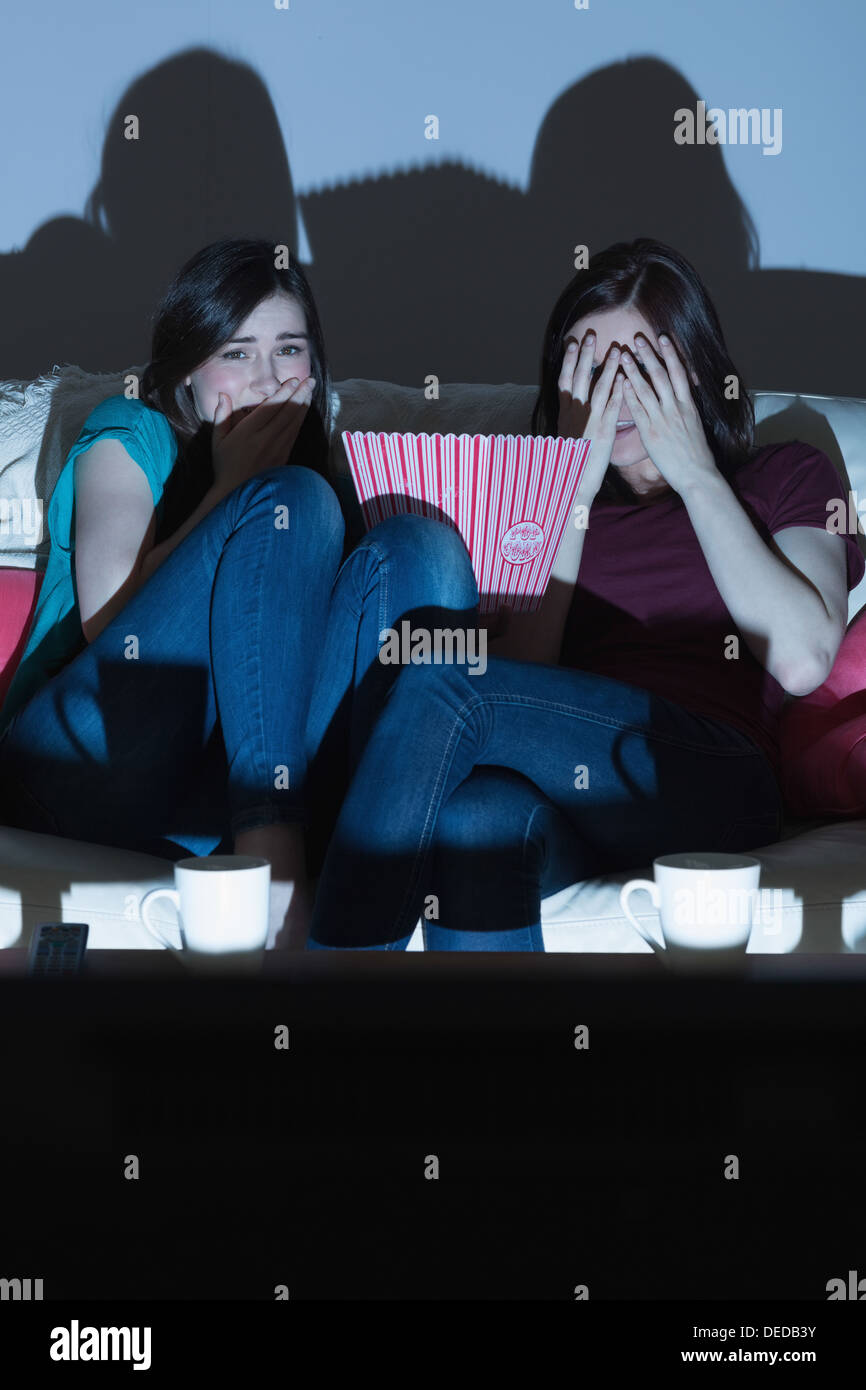 Due amici sul divano guardando un film spaventoso insieme al buio Foto Stock