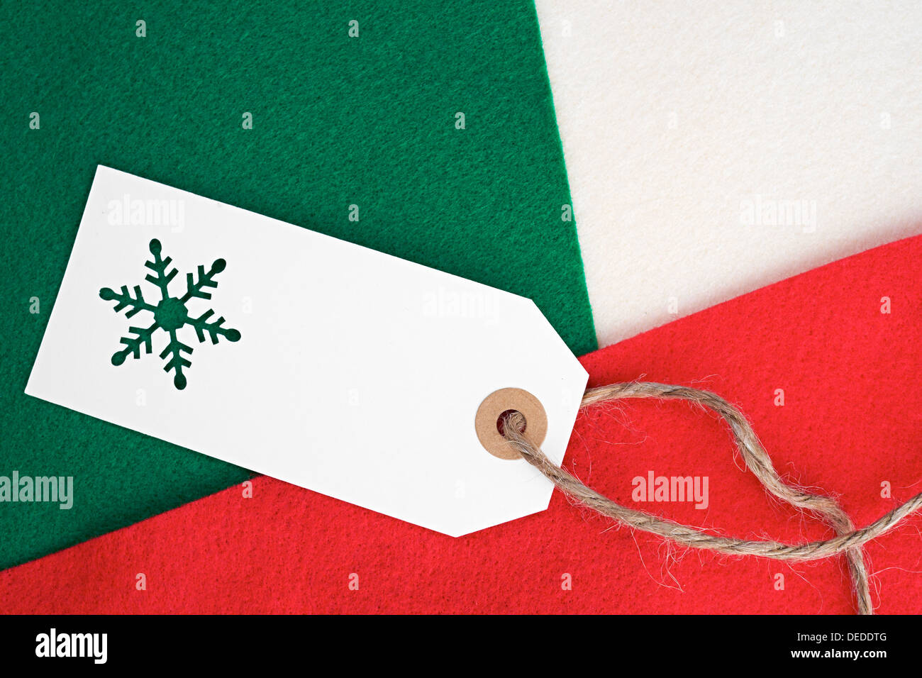 Regalo di natale tag su un rosso, verde e crema di materiale in feltro sfondo. Foto Stock