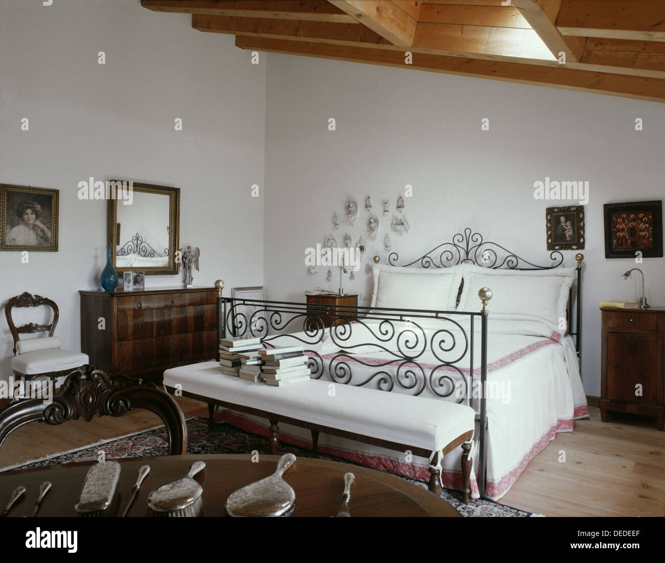 Camera da letto con mobili antichi in soffitta e tetto in legno Foto Stock