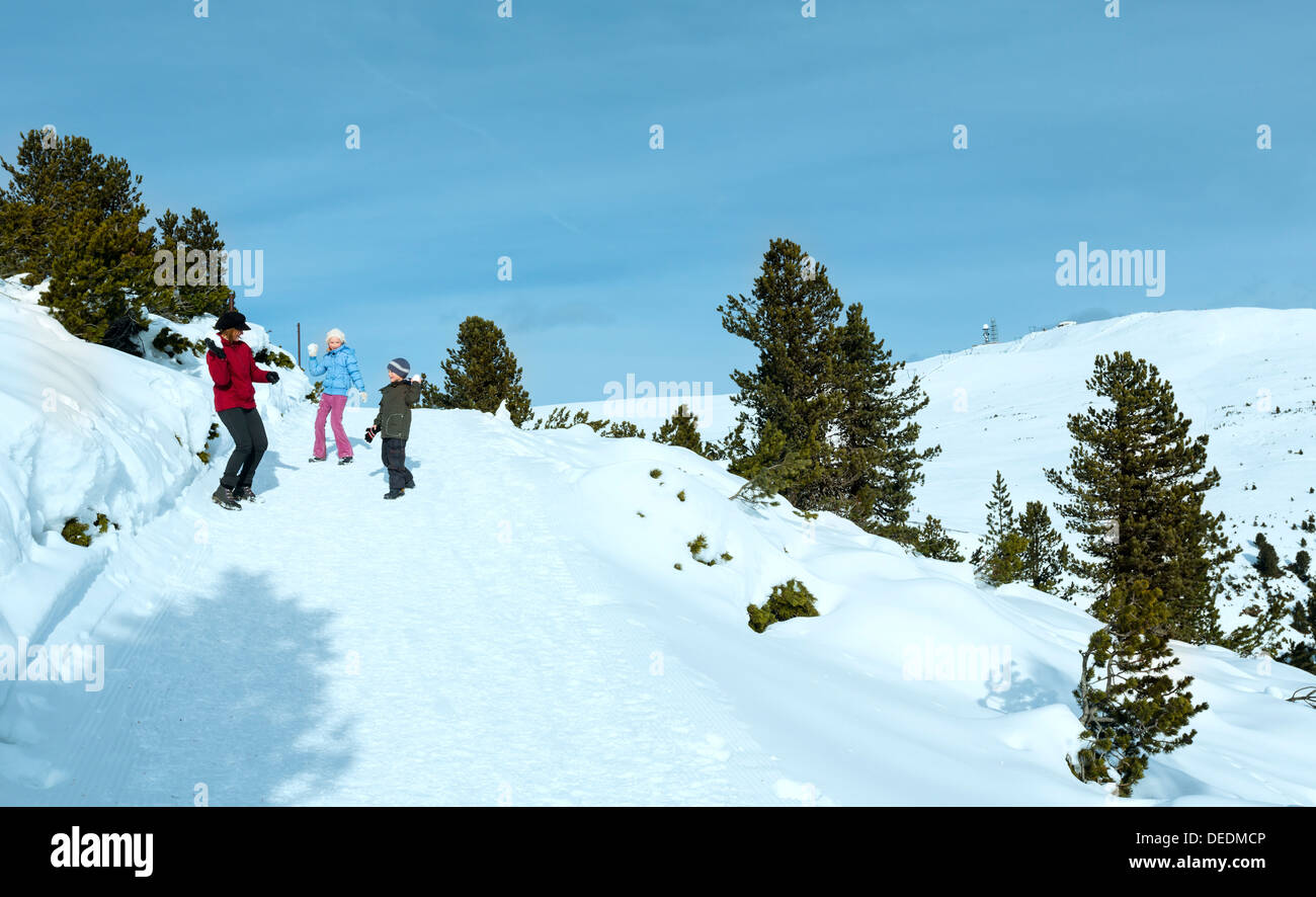 La famiglia (madre di due figli) gioca a snowballs in inverno pendio di montagna Foto Stock