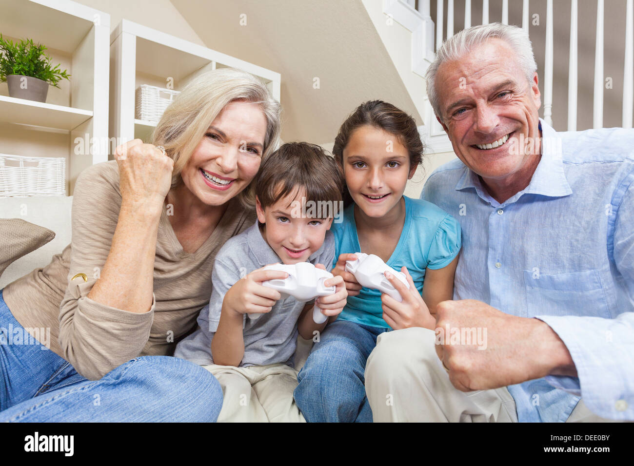 Senior adulti e bambini, nonni, nipote e nipote, famiglia divertendosi console video games insieme Foto Stock