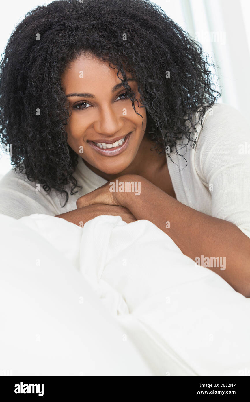 Ritratto di un bellissimo centro di età americano africano donna seduta a casa rilassarsi sorridendo o ridendo Foto Stock