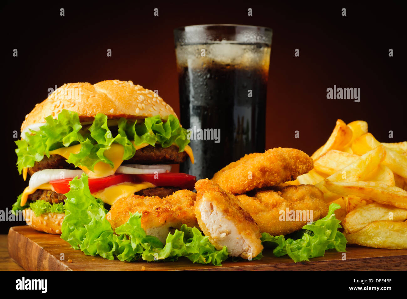 Il fast food con hamburger o cheeseburger, pepite di pollo e patatine fritte e bevanda di cola Foto Stock