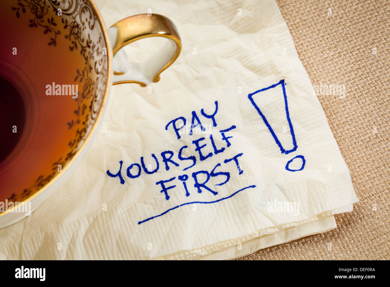 Te stesso prima pagare, un promemoria delle finanze personali strategia - un tovagliolo doodle con una tazza di tè Foto Stock