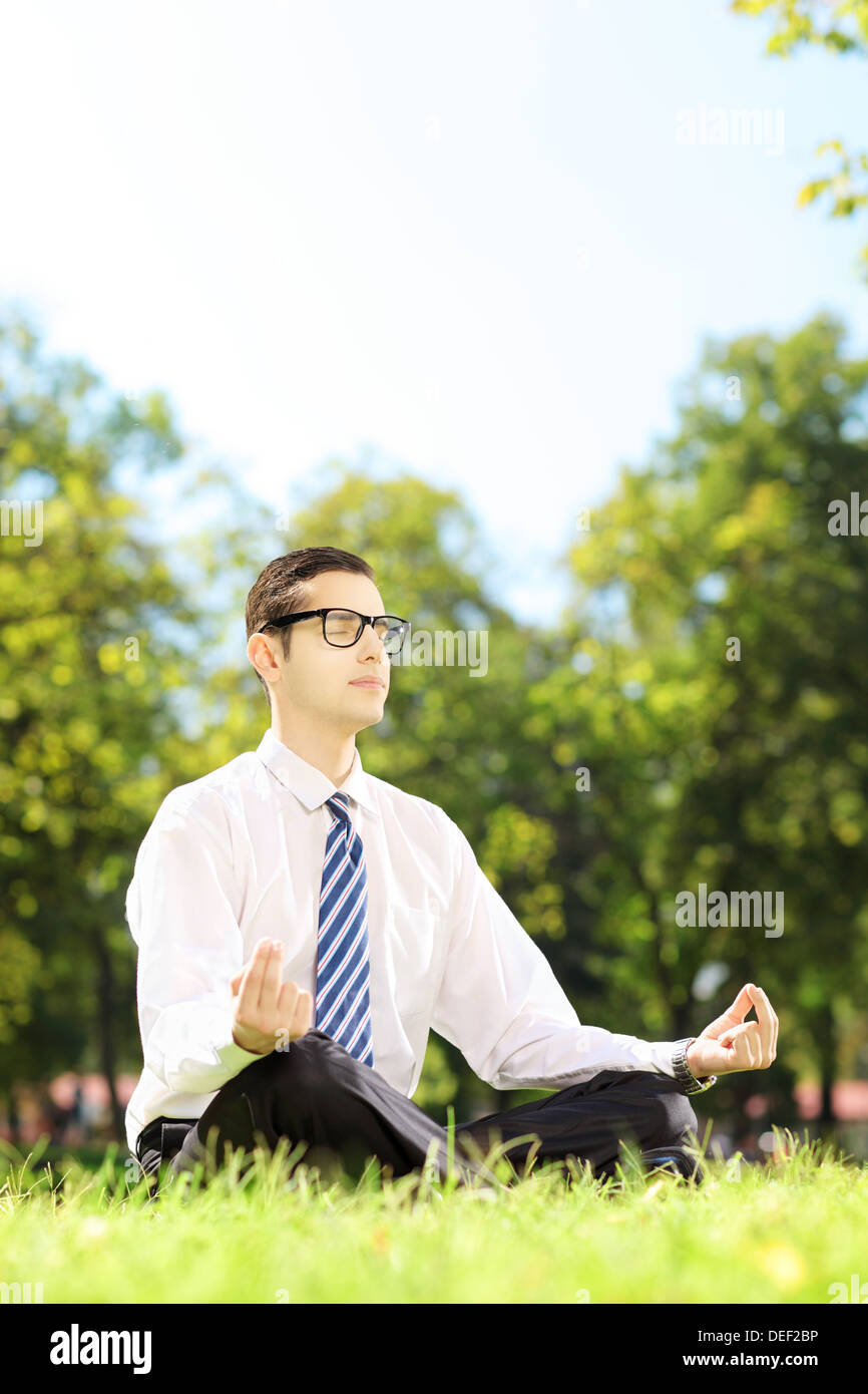 Giovani imprenditori con occhiali meditando seduto su un prato in un parco Foto Stock