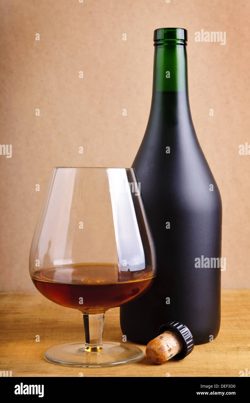 Vetro e bottiglia di cognac con sughero su uno sfondo di legno Foto Stock