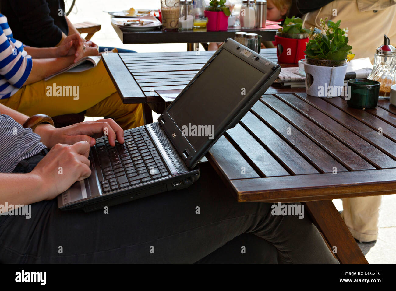 Persona che usa il computer portatile in un ristorante esterno tabella Foto Stock