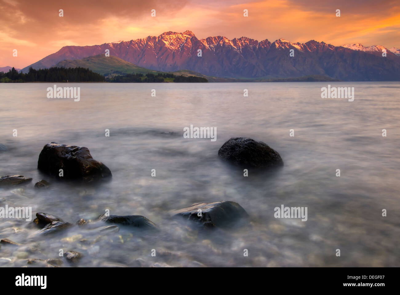 La catena montuosa Remarkables accesa fino al tramonto sul lago Wakatipu, Queenstown, South Island, in Nuova Zelanda. Foto Stock