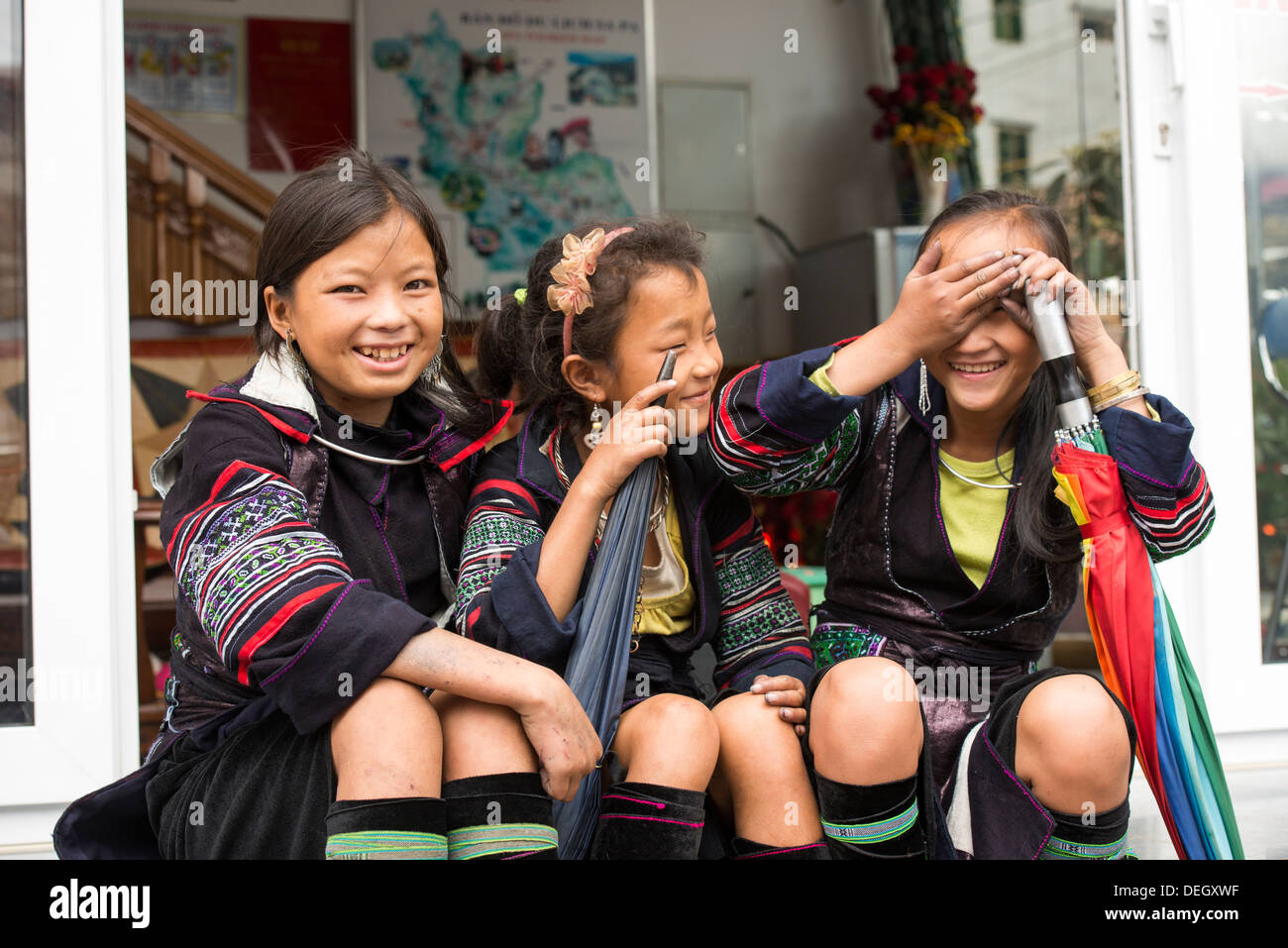 Bambine sedersi su accanto a downtown street indossare il costume tradizionale, Sa Pa, Vietnam Foto Stock