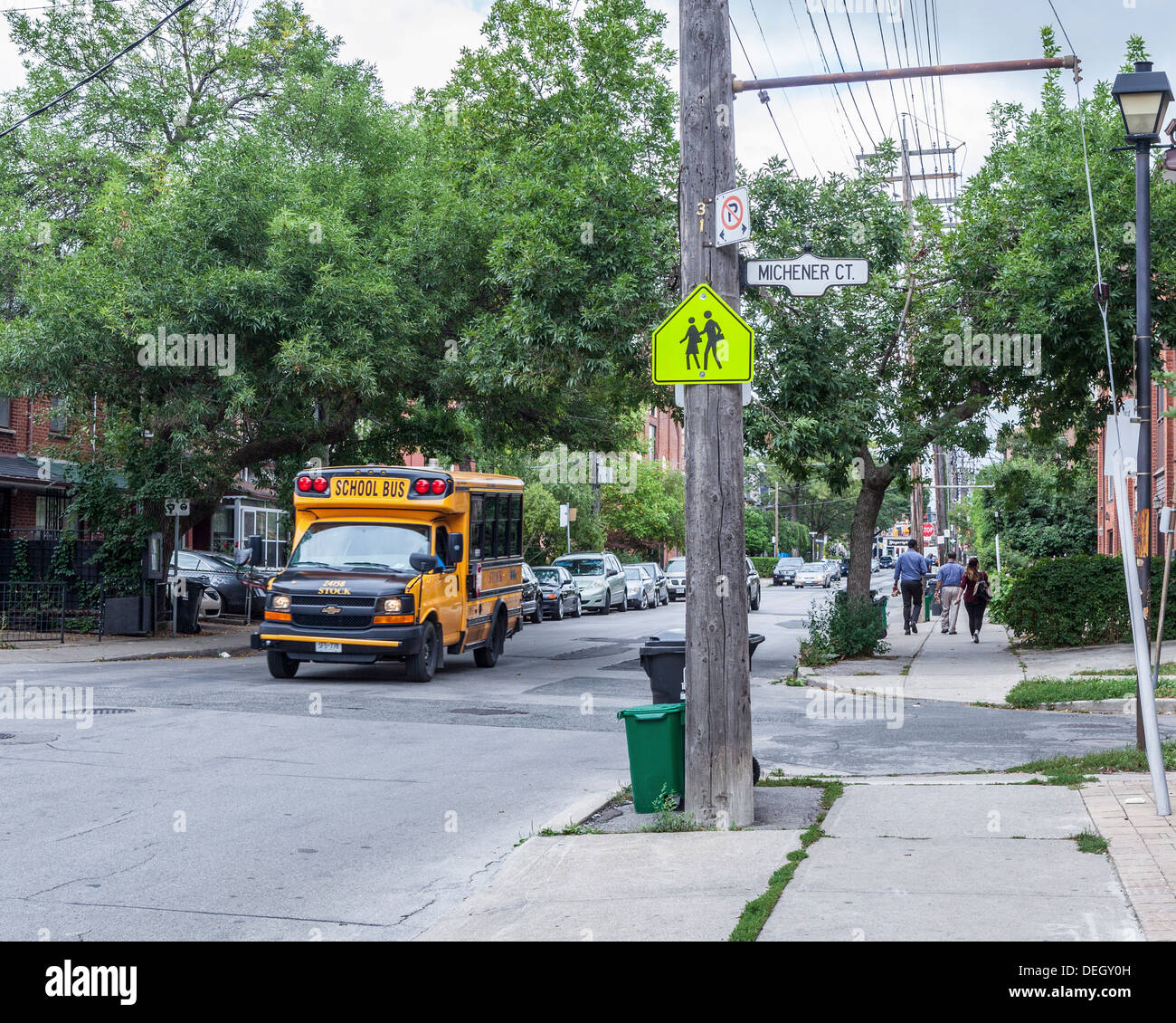 Un giallo scuola bus e un segno di avvertimento di anziani incrocio su una strada di Toronto Foto Stock