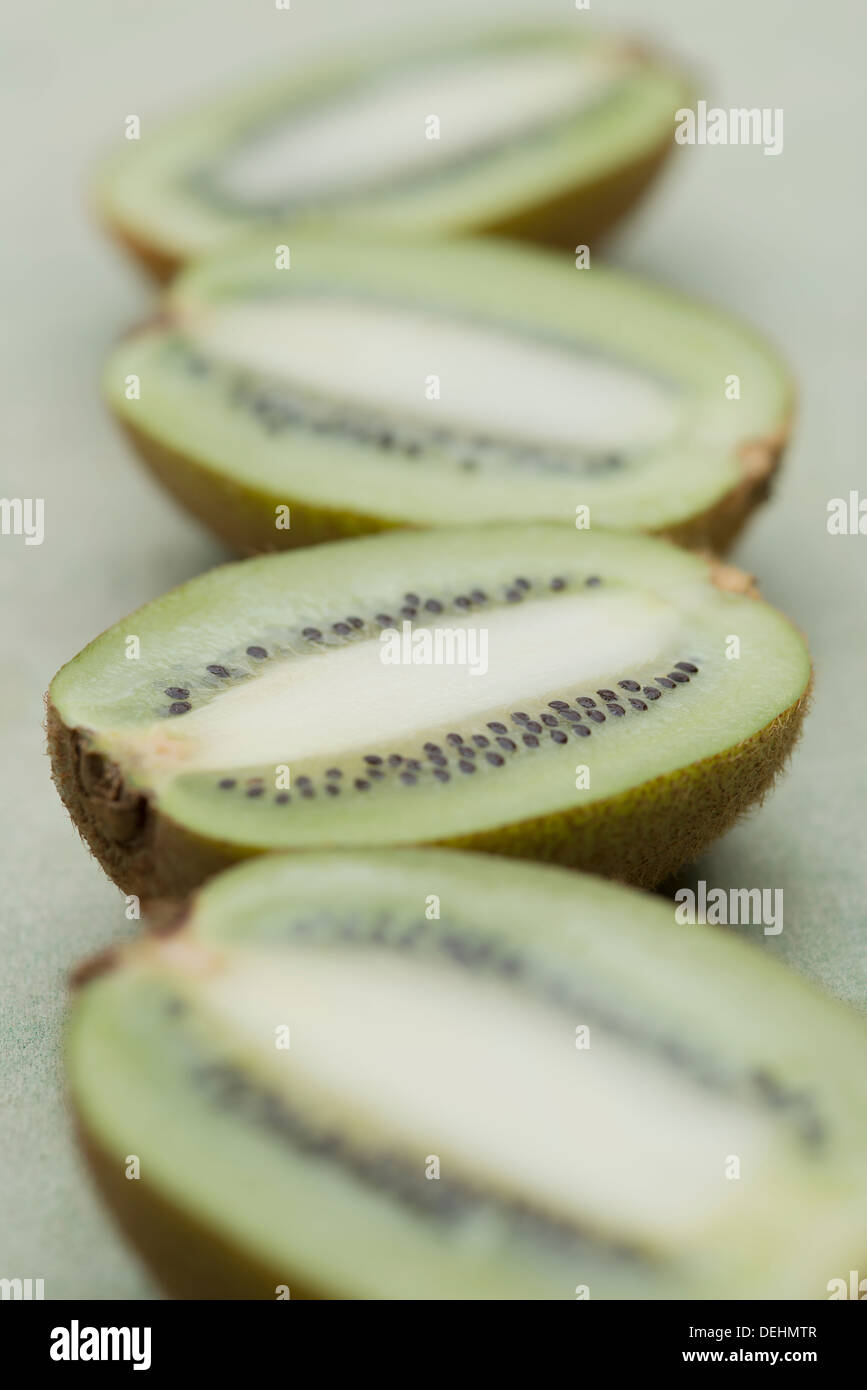 Succoso e appetitoso fresche kiwi tagliati a metà e disposti in fila su una superficie in legno Foto Stock