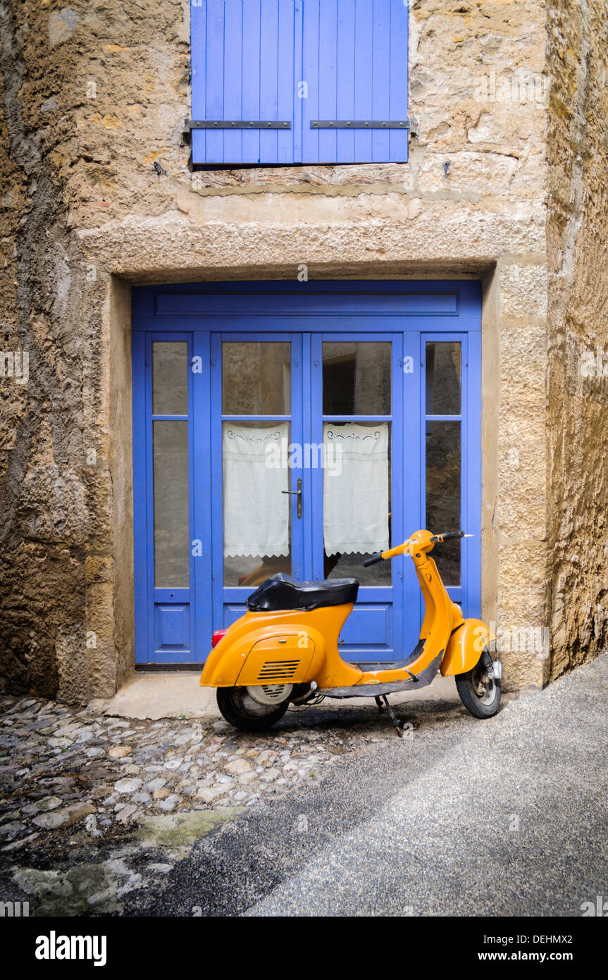 La quintessenza della scena francese girevole intorno ad un arancio scooter e una combinazione di lavanda porte e persiane blu. Foto Stock