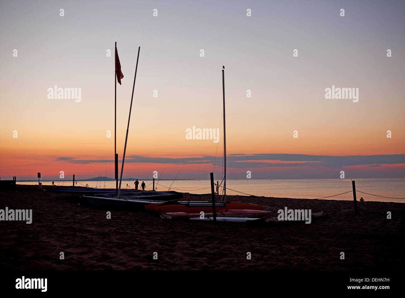 Sagome di barche e gente sulla spiaggia dal tramonto Foto Stock