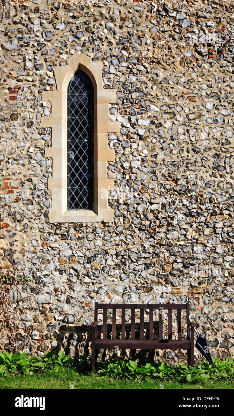 Una lancetta finestra e sedile con ombrellone al di fuori di un North Norfolk chiesa. Foto Stock