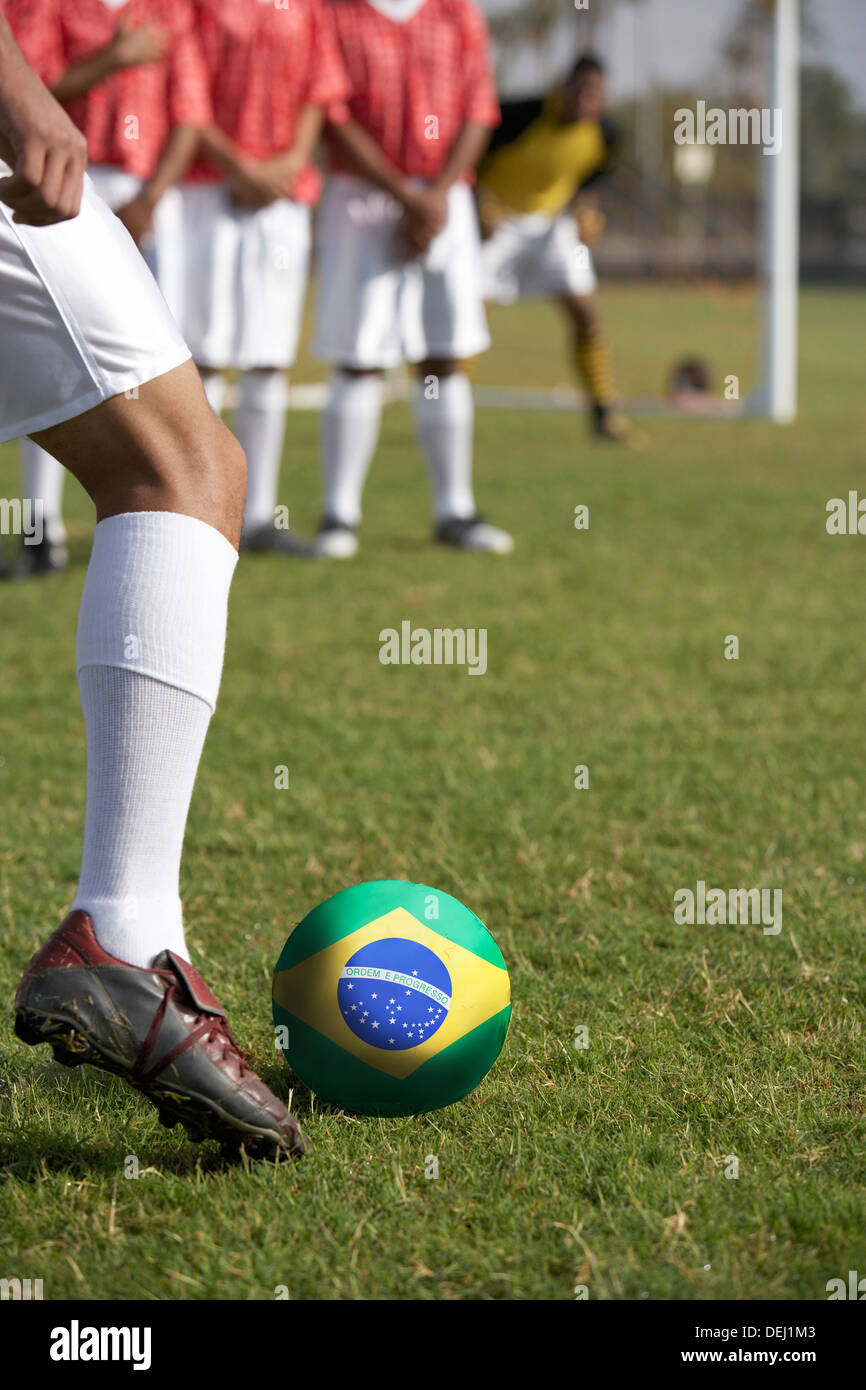 I giocatori di calcio per la preparazione di un calcio di punizione anteriore bandiera brasiliana Foto Stock