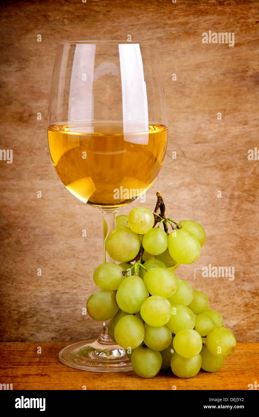 Bicchiere di vino bianco e uva su un annata sullo sfondo di legno Foto Stock