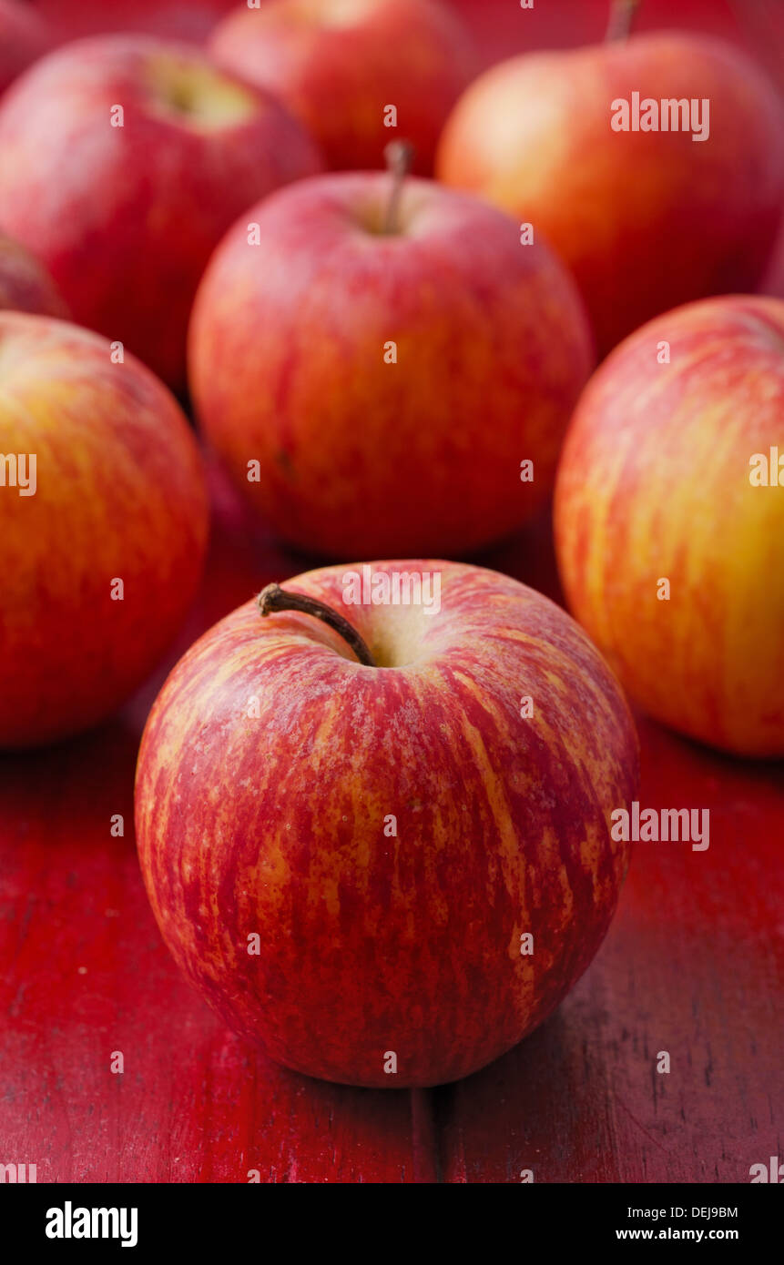 Diverse le mele rosse sulla tavola di legno rosso Foto Stock