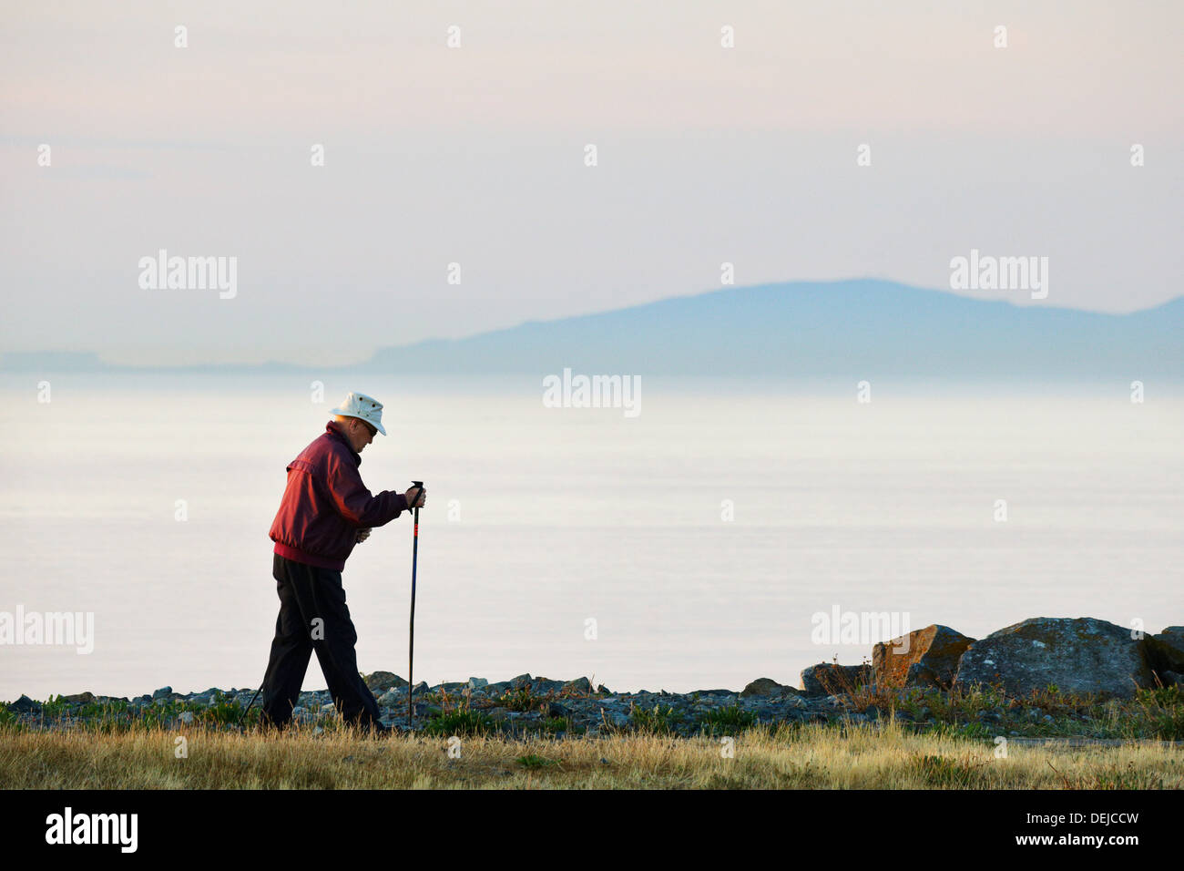 Uomo anziano a piedi a Oak Bay marina a sunrise-Victoria, British Columbia, Canada. Foto Stock