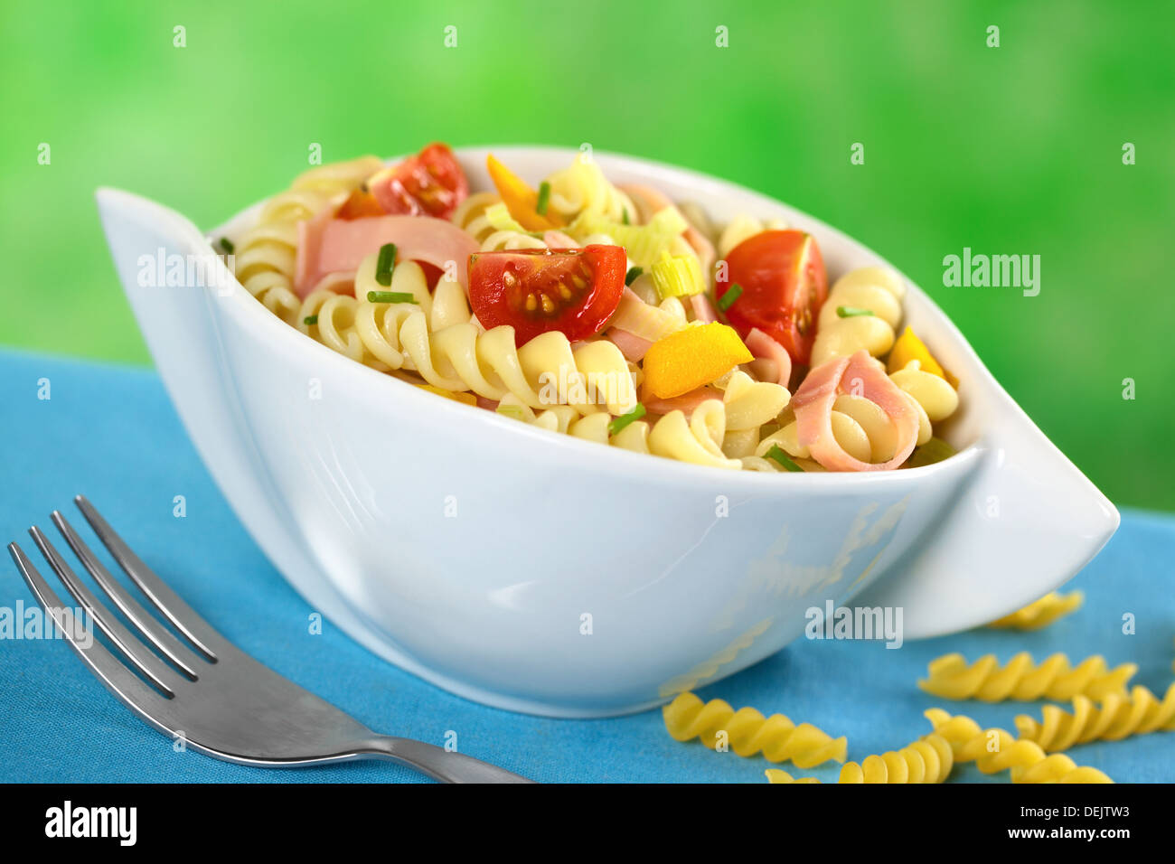 Insalata di pasta con il porro, cherry pomodoro, peperone giallo e prosciutto guarnita con erba cipollina Foto Stock
